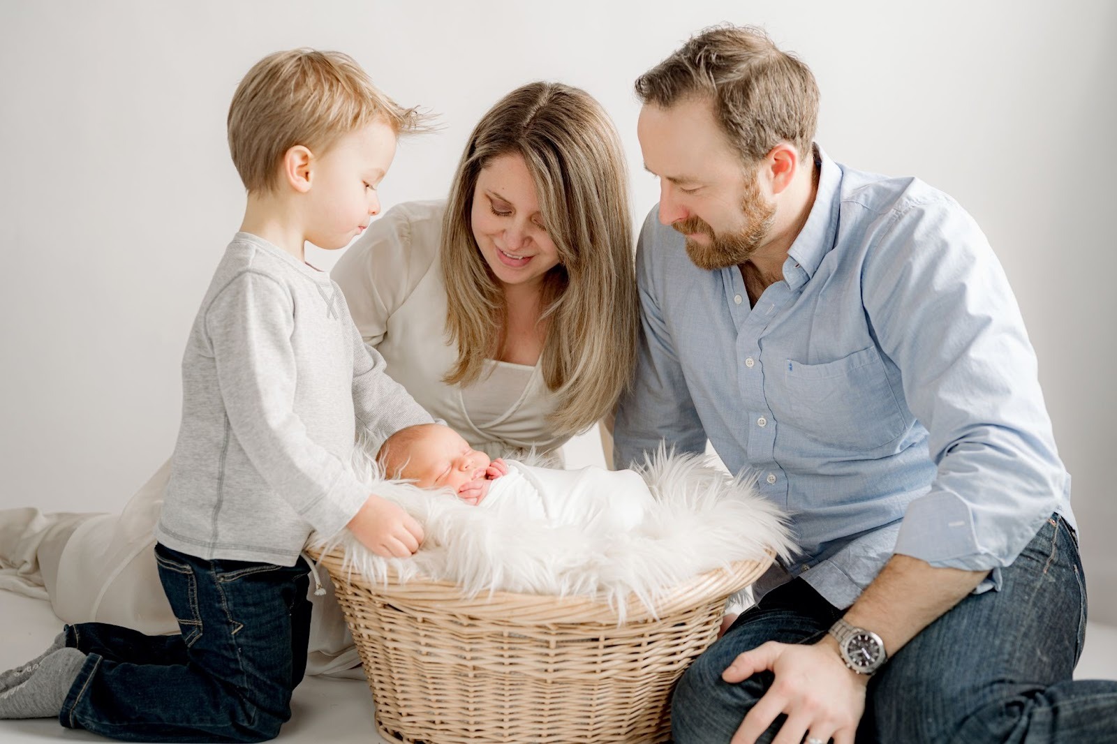 Family gathered around a photo of a newborn in a basket